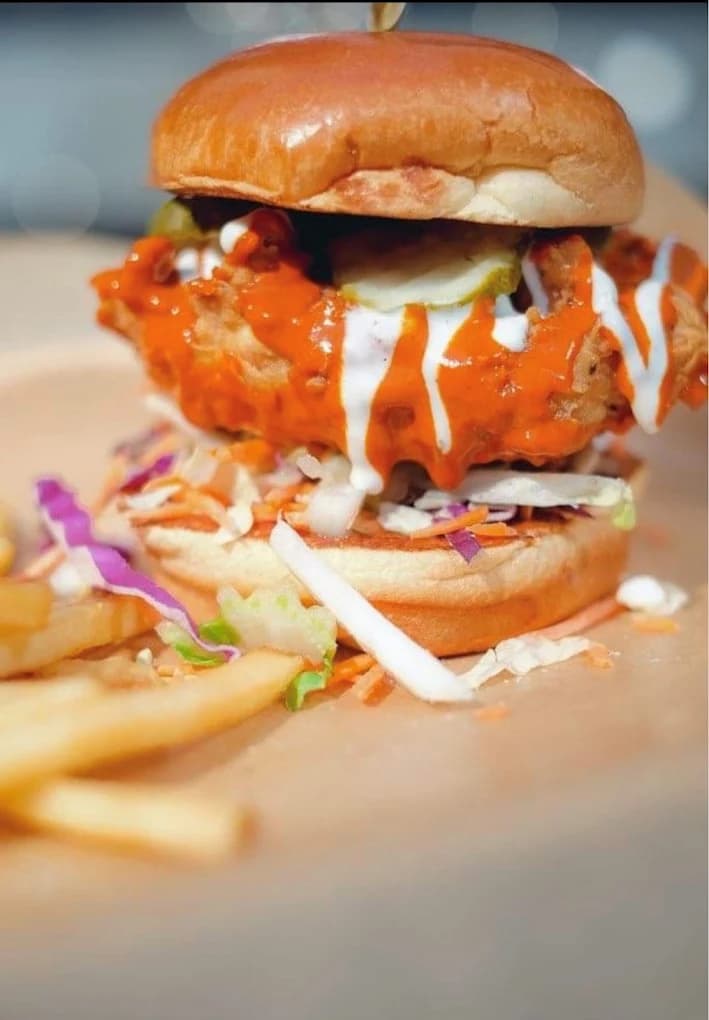 Buffalo fried chicken sandwich with ranch, pickles and slaw on a brioche bun