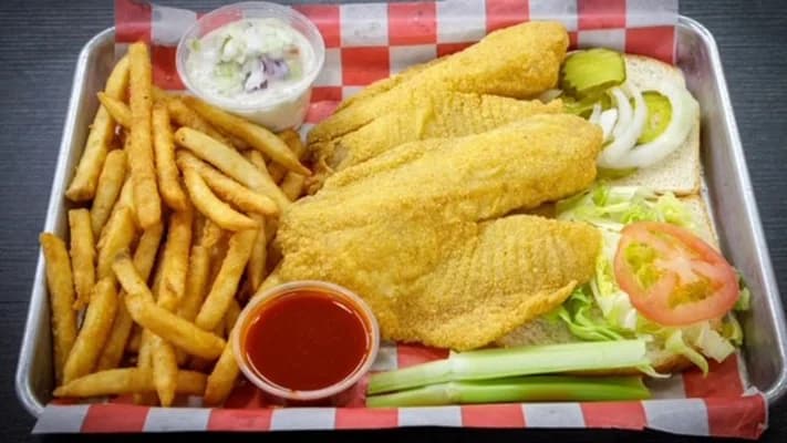 Fried fish fillets with fries, coleslaw and hot sauce